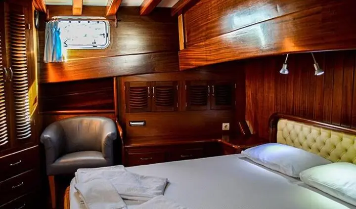 Cozy yacht cabin with a large bed, wooden panels, and built-in cabinets