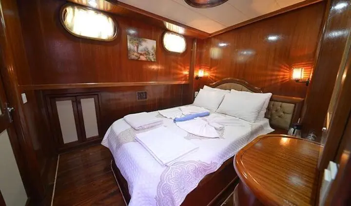 Master cabin with large bed, white linens, wood-paneled walls, and bedside lamps