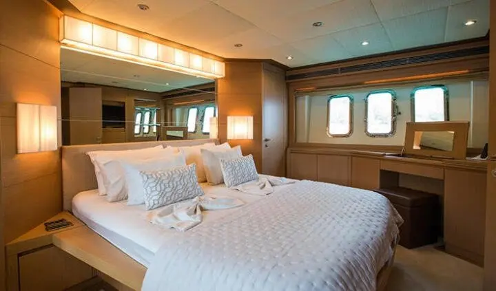 Master cabin with two single beds pushed together, white linens, wooden walls, and ensuite doorway