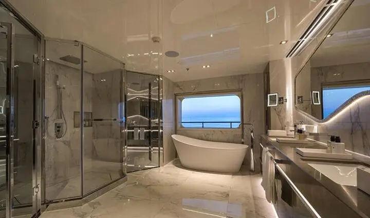 Marquise cabin interior with bed, glass walls, panoramic sea view, warm lighting