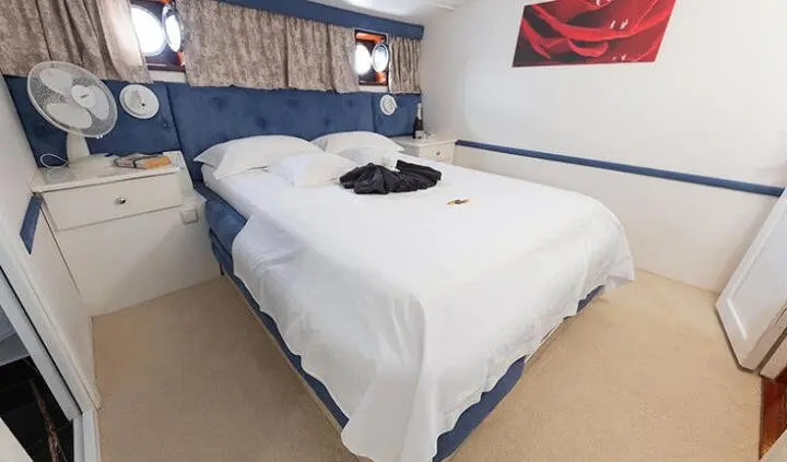 Aurum yacht master cabin with a king bed, white linens, and ensuite doorway