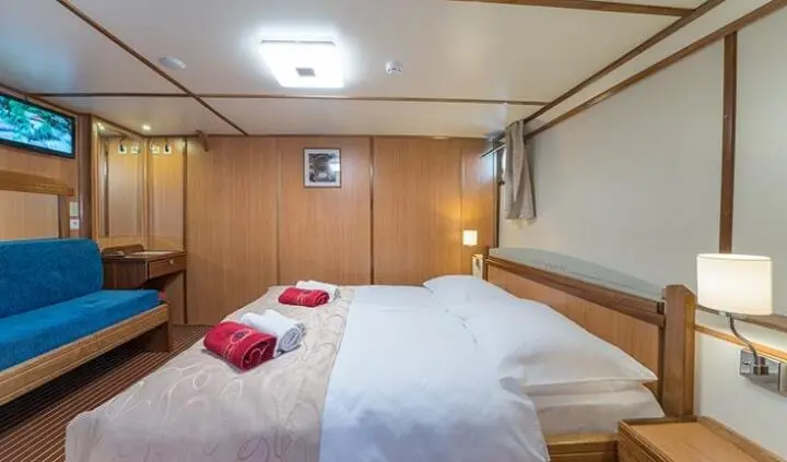 Yacht Barbara cabin with two single beds, pillows, wood paneling, and overhead storage