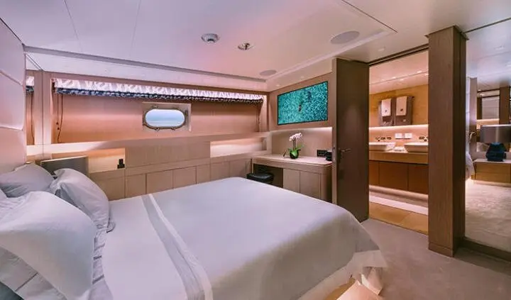 Xana yacht cabin with double queen bed, porthole, wood panels, and flat-screen TV