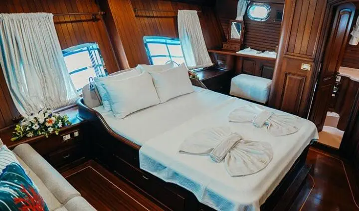 Master cabin with a large bed, white linens, and wood interior on Wicked Felina
