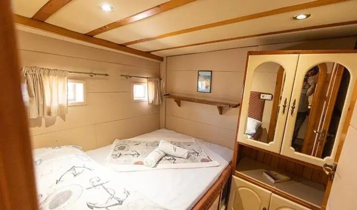 Gardelin cabin interior with double bed, compact wood cabinetry, and mirrored wardrobe