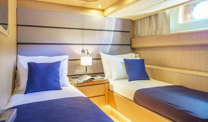 Twin cabin berth with blue pillows and wood-paneled walls on yacht Phantom
