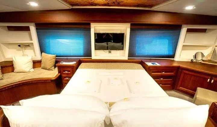 Master cabin with queen bed, wood tones, overhead lighting, ensuite doorway