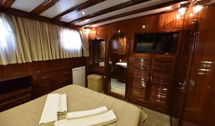 Cozy yacht cabin with wooden cabinetry, bed, and soft lighting