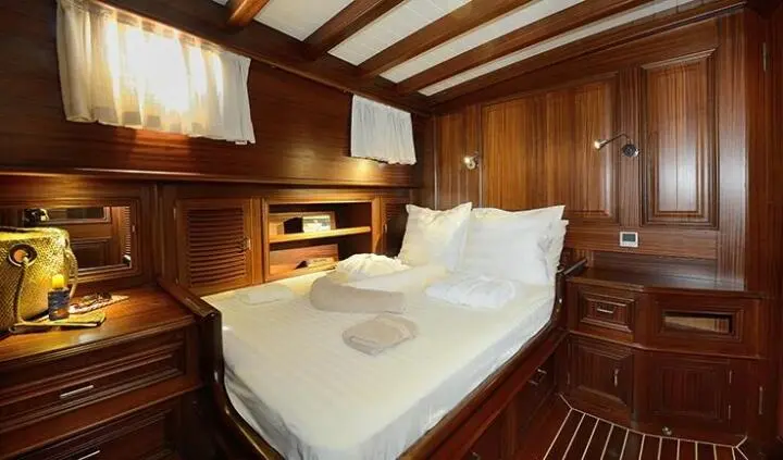 Cozy yacht cabin with wooden paneling, two single beds, and warm lighting