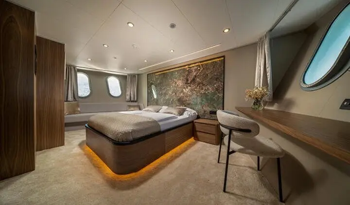 Master cabin on Olimp yacht with king bed, ensuite area and warm lighting
