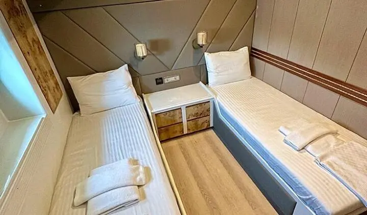 Twin cabin with two single beds and shared nightstand on wood floor