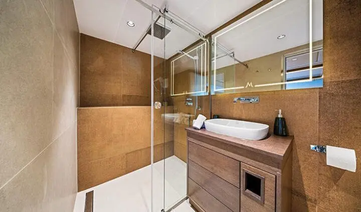 Master cabin with wood panels, ensuite shower glass door, and bed