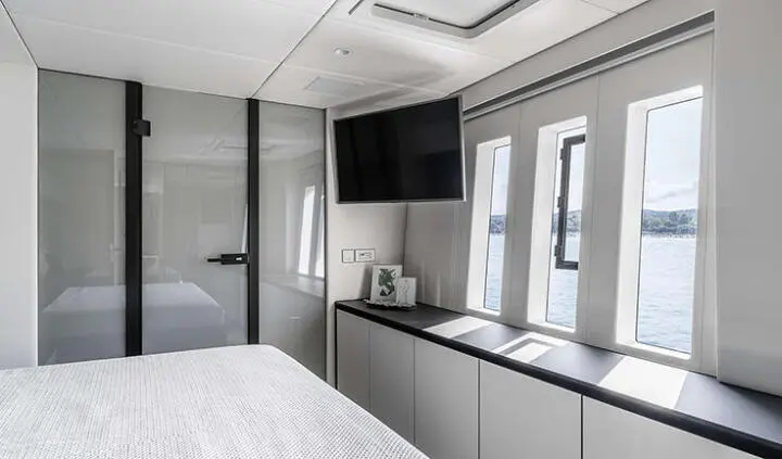 Master cabin with king bed, ensuite, grey and white decor, TV on wall