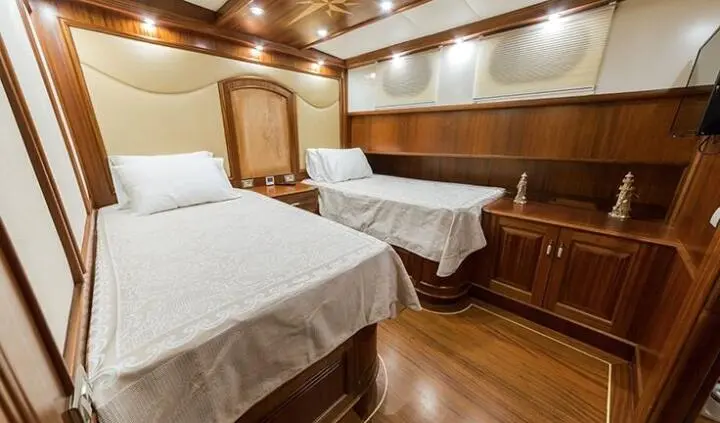 Twin cabin onboard Halcon Del Mar with two beds, wooden furniture, and warm lighting