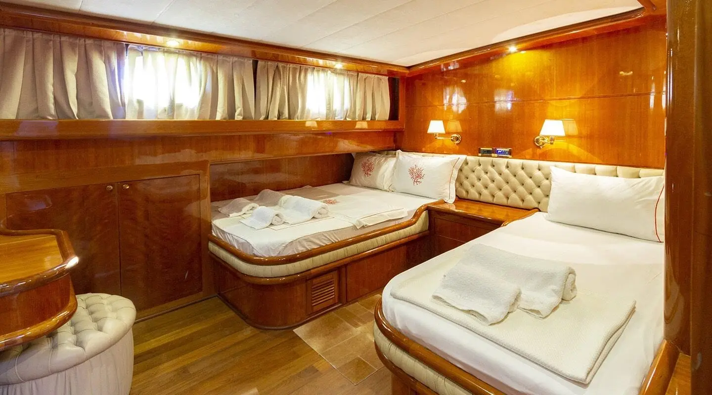 Luxury yacht interior with two twin beds, wood paneling, warm lighting