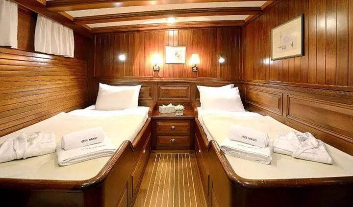 Twin cabin interior on Ecce Navigo yacht with two single beds and wood paneling