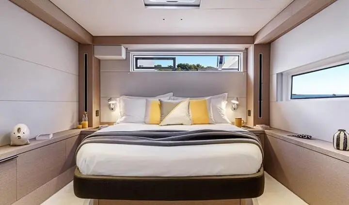 Daiquiri yacht cabin with large bed, white linens, and yellow accent pillows