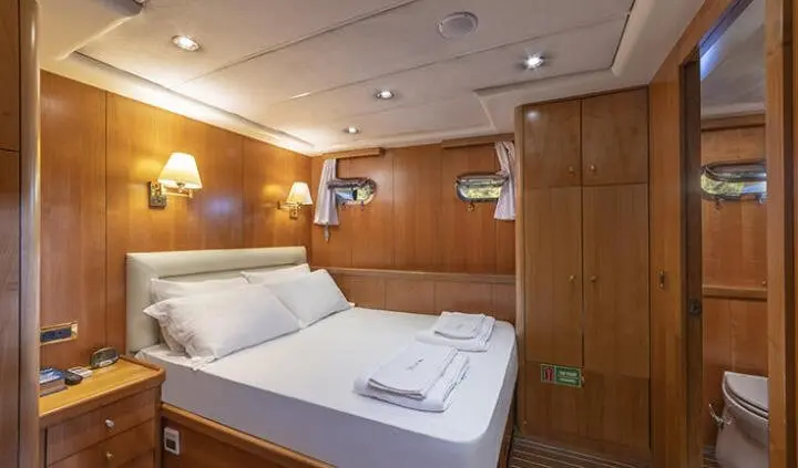 Queen Of Sea yacht cabin interior with two white beds and wooden panels