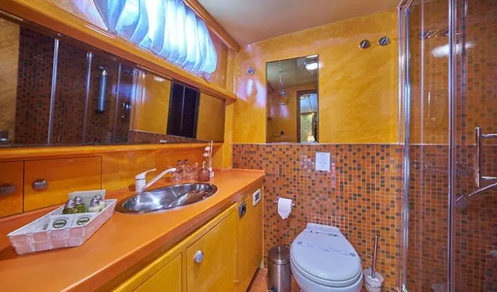 Compact cabin bathroom aboard Lotus yacht with wooden cabinetry and toilet