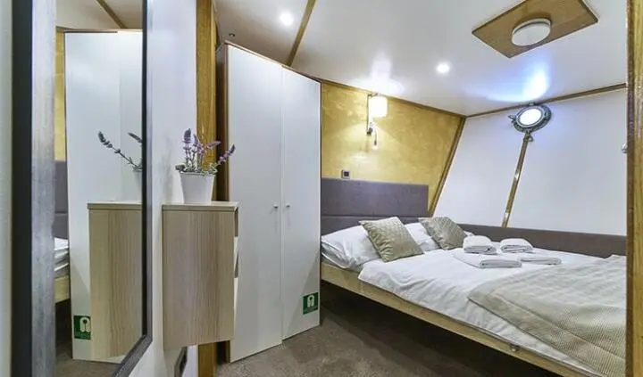 Deluxe cabin on Romanca yacht: neatly made bed, wardrobe, and interior lighting