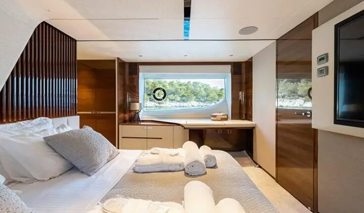 Vista yacht cabin with a large bed, white linens, and a window view
