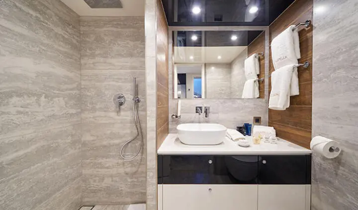 Master cabin with king bed, beige bedding, wooden shelves, ensuite area visible