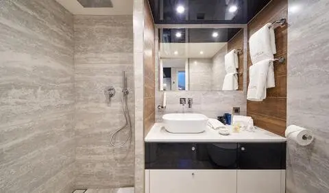 Master cabin with king bed, beige bedding, wooden shelves, ensuite area visible