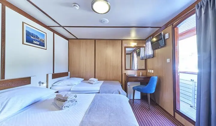 Twin cabin with two beds on Amorena yacht, wood cabinetry and blue accents