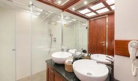 Bathroom ensuite aboard Lady Gita yacht, double sinks, glass shower, wooden cabinetry