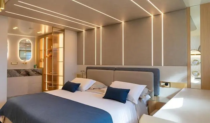 Master cabin with king bed, navy and white linens, ensuite door visible