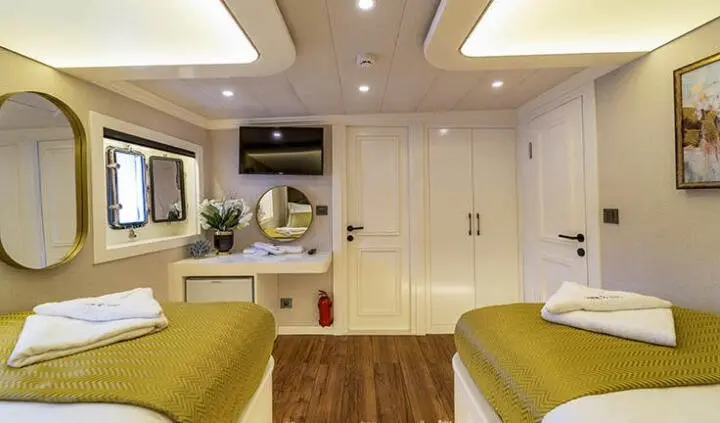 Twin cabin aboard Queen Of Makri yacht with two single beds and interior lighting