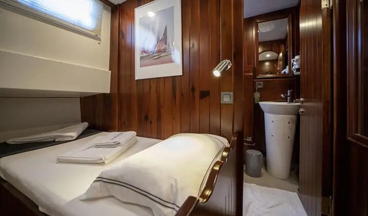 Double cabin with wood paneling, two single beds, bedside items, compact storage