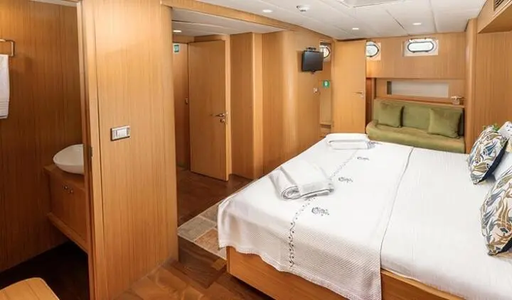 Master cabin with a large bed, wooden walls, and built-in wardrobes
