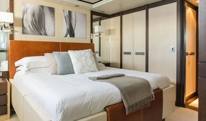 Master cabin with king bed, white bedding, brown headboard, windows on left