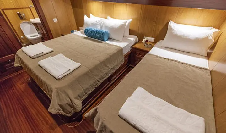 Kayhan 3 yacht cabin with two single beds, blue pillows, and linens