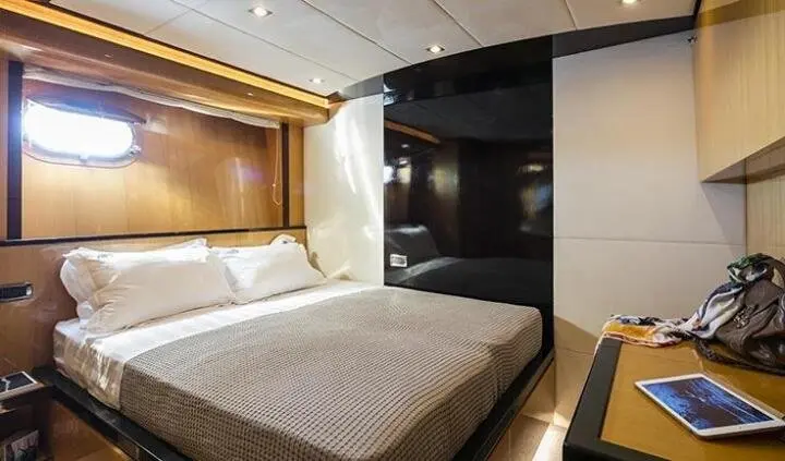 Cozy yacht cabin with a large bed, white linens, wooden headboard, and warm lighting
