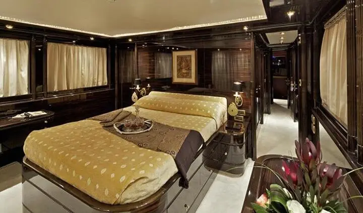 Yacht cabin with two single beds, brown headboards, beige bedding, and lighting