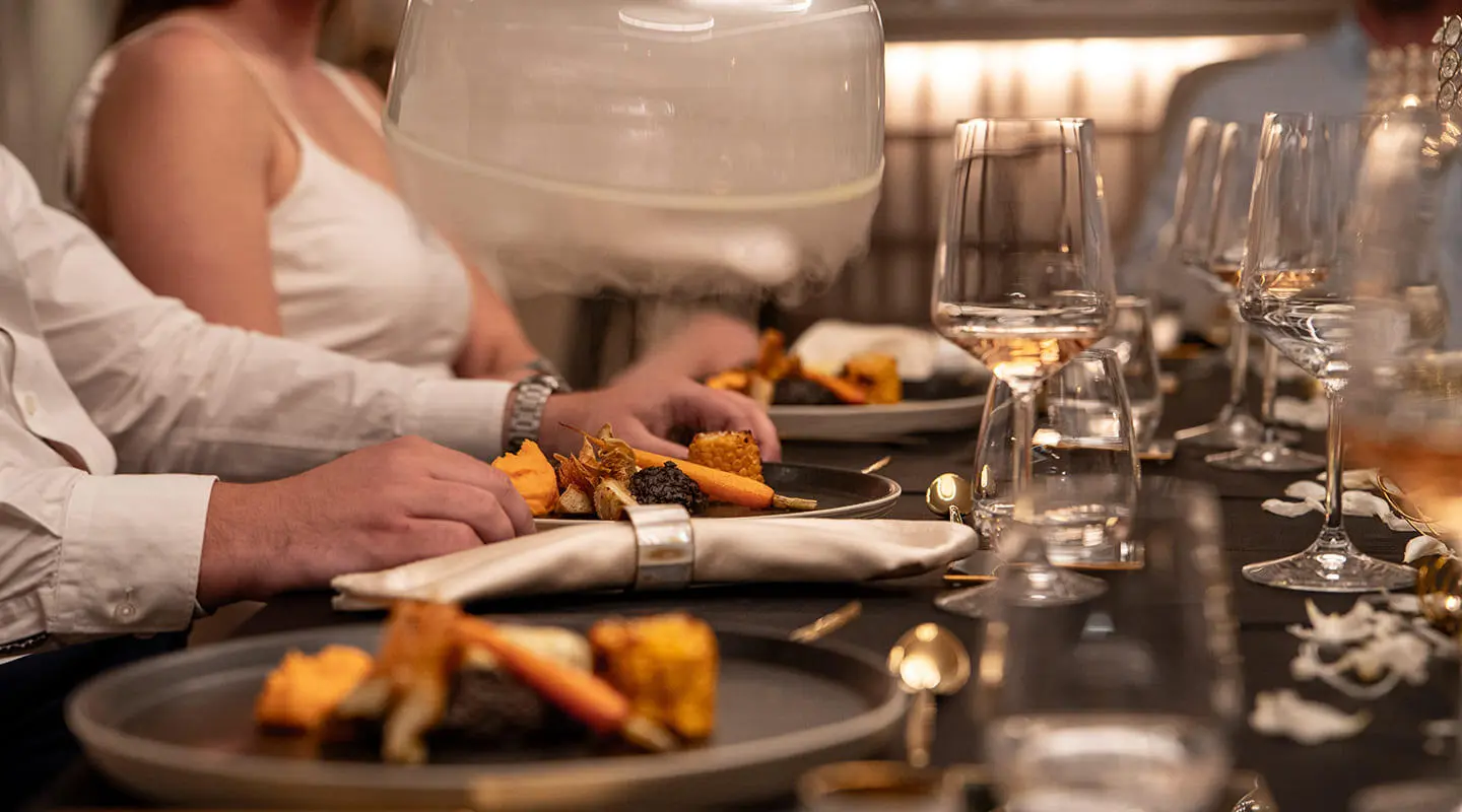 Nocturno yacht dining deck scene with plated meals and guests