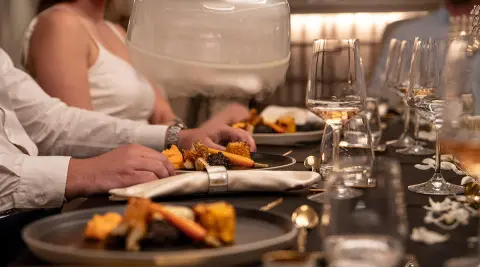 Nocturno yacht dining deck scene with plated meals and guests