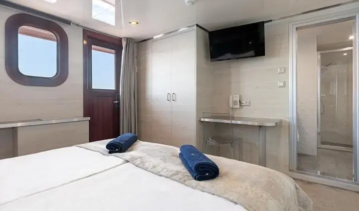 YachtYOLO cabin with bed, navy pillows, compact kitchenette, beige walls