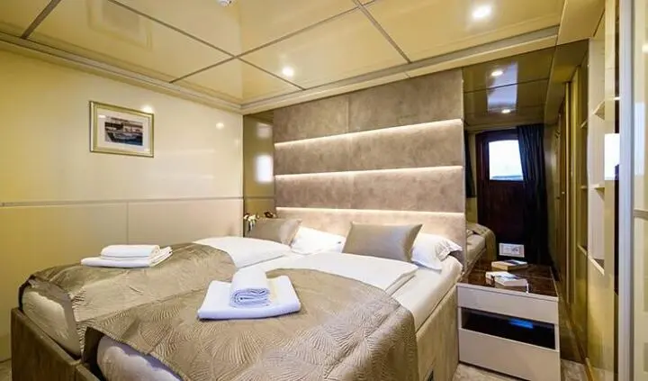 Master cabin with king bed, beige bedding, padded headboard, ensuite visible