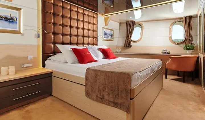 Queen Eleganza cabin interior with a double bed, brown accents, and pillows