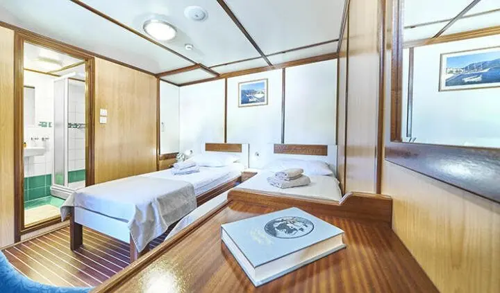Amorena cabin twin beds yacht interior with large windows and wooden flooring