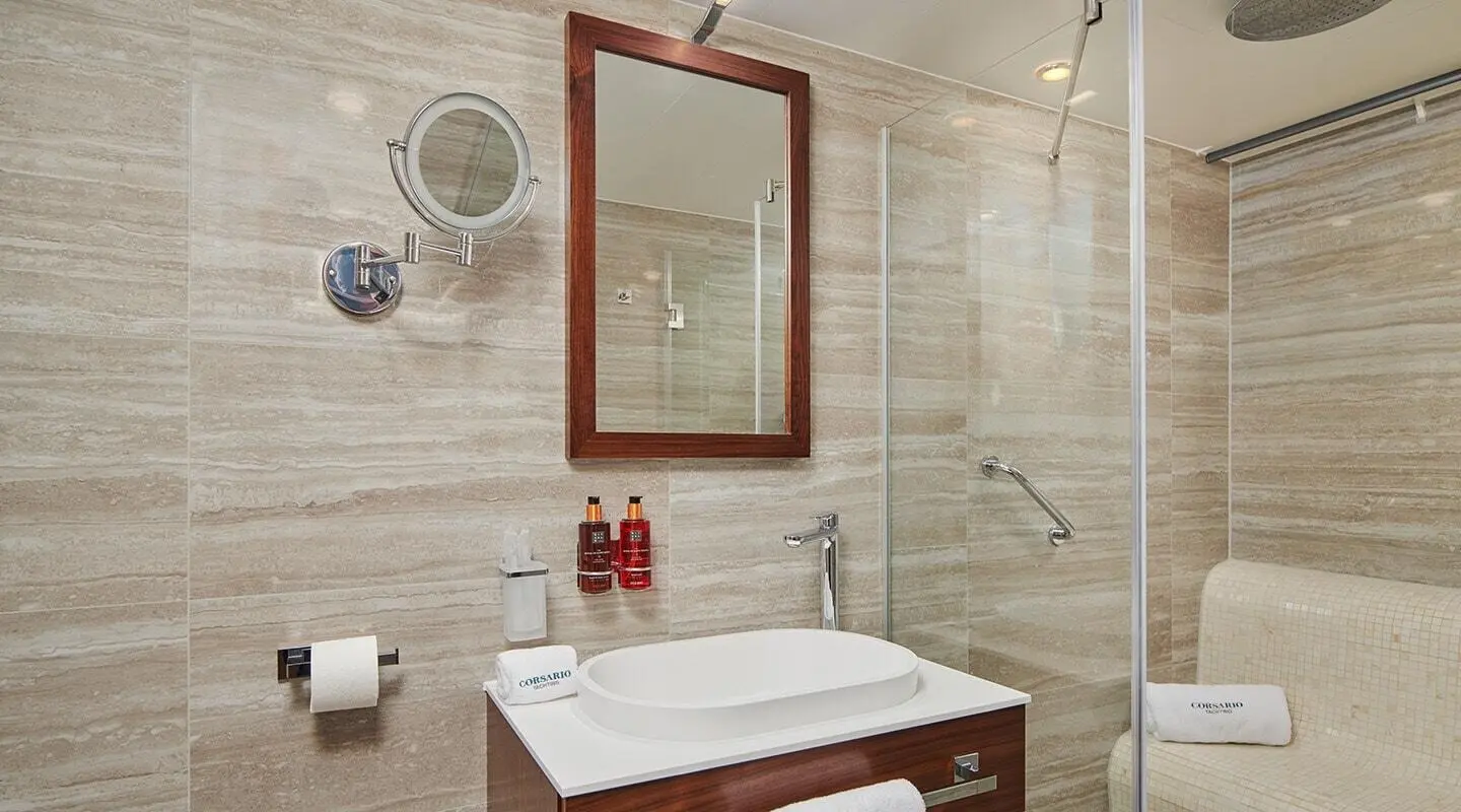 Corsario yacht bathroom with tiled walls, mirror, sink, and red soap dispenser