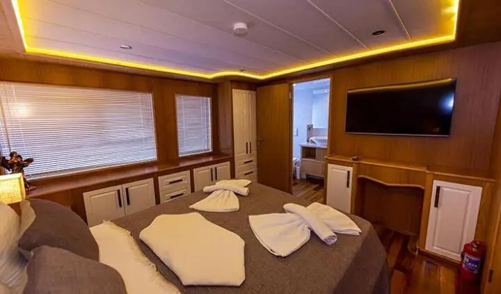 Master cabin with king bed, beige linens, wood cabinetry and ensuite area
