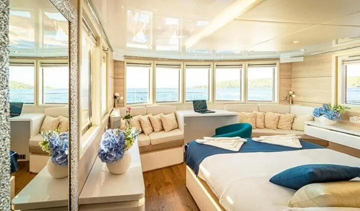 Luxurious yacht cabin with a king bed, plush seating, and large windows
