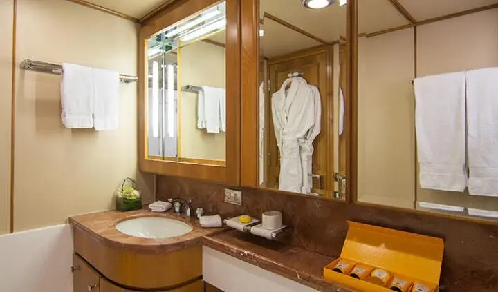 Master cabin with king bed, ensuite, wood paneling, mirror, and seating