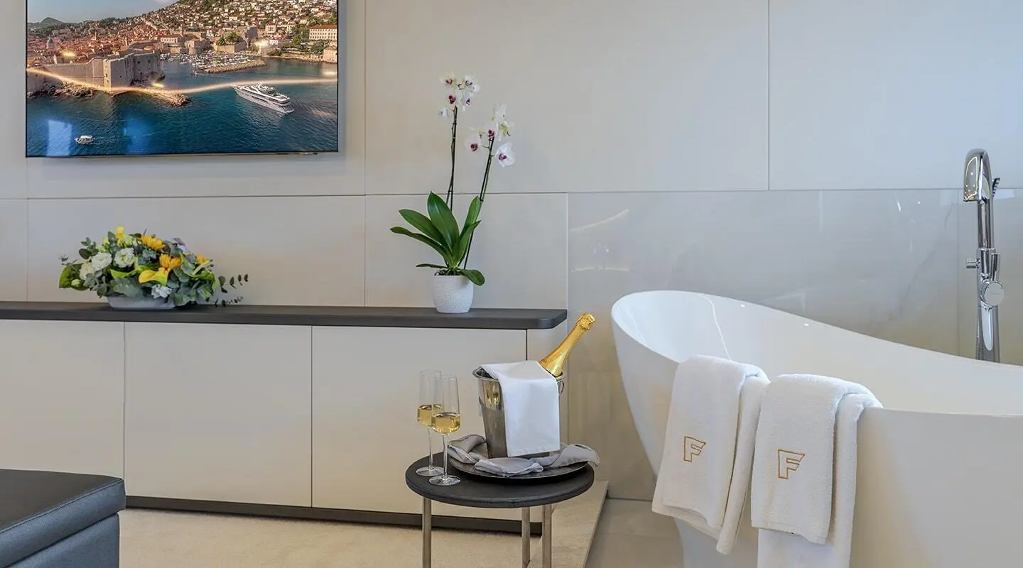 Elegant interior of a yacht with a white round table, chair, and a vase on a sideboard during evening light
