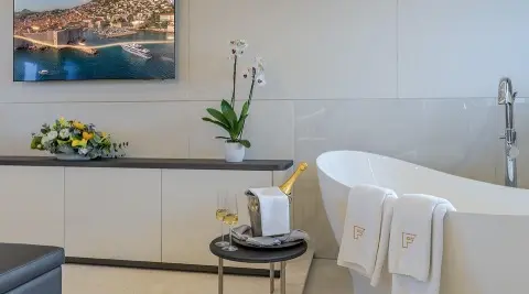 Elegant interior of a yacht with a white round table, chair, and a vase on a sideboard during evening light