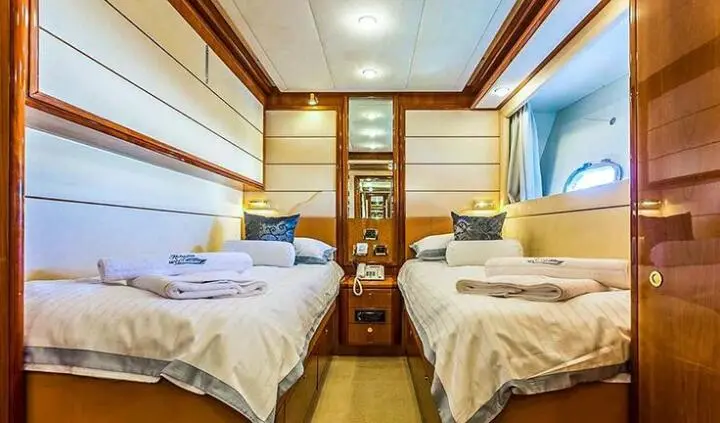 Twin cabin with two single beds, shared ensuite, wood cabinets, porthole window